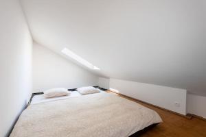 a white bedroom with a bed with two pillows at Astronomical Clock Apartment in Prague