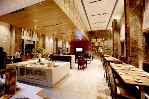 a restaurant with tables and chairs in a room at Hotel Madin in Varanasi