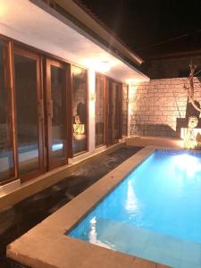 a swimming pool in front of a house at night at Pranajayaloka private villa in Tejakula