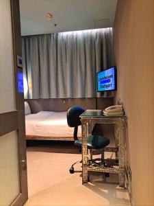 Cette chambre comprend un lit et un bureau avec une chaise. dans l'établissement IND Hotel, à Hong Kong