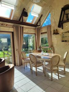 a dining room with a table and chairs and windows at La Vendemiere - Maison d'hôtes de charme et de caractère, Bretagne, Côtes d'Armror in Pont-Melvez