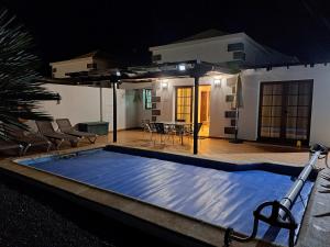 a swimming pool at night with a house in the background at Villa de la Paz in Playa Blanca