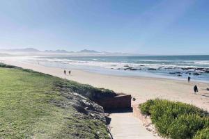 a group of people walking on a beach at The Perfect Hartenbos Holiday Home in Mossel Bay