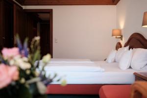 ein Hotelzimmer mit einem Bett mit weißer Bettwäsche und Kissen in der Unterkunft Hotel Traube Tonbach in Baiersbronn