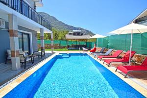 a swimming pool with chaise lounge chairs and umbrellas at Villa Kozalak 1 in Fethiye