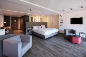 a bedroom with a bed and two chairs and a television at Hotel Traube Tonbach in Baiersbronn