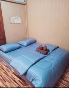 a teddy bear laying on top of a blue bed at Nadan Beach House in Ban Thung O