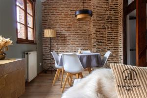 a dining room with a brick wall and a table and chairs at The Nest, parking, centre, vue sur la Cathédrale in Albi