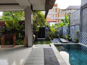 un patio trasero con piscina y una casa en Villa Lovecho, en Canggu