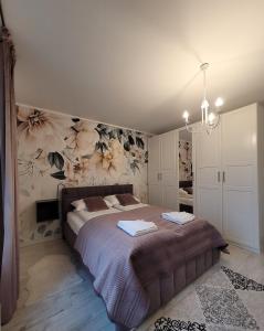 a bedroom with a bed with flowers on the wall at Horyzont Apartamenty-ANTON-Piękny apartament blisko centrum, dwie sypialnie, prywatny garaż in Kołobrzeg