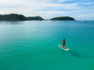 a man standing on a surfboard in the water at The Nai Harn in Nai Harn Beach