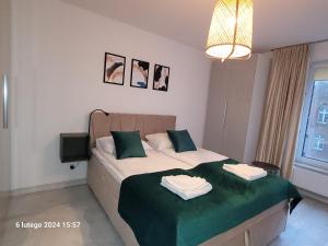 a bedroom with a bed with two towels on it at Horyzont Apartamenty-ANTON-Piękny apartament blisko centrum, dwie sypialnie, prywatny garaż in Kołobrzeg +6 photos