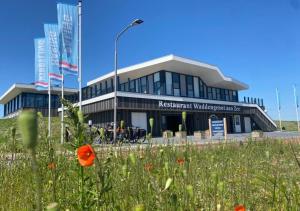 a building with a field of flowers in front of it at Hotel Waddengenot in Pieterburen