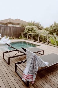 a deck with a table and chairs next to a pool at Maison De Plage in Umdloti