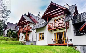 a house with a green lawn in front of it at Wonder Home - Domki górskie na osiedlu dozorowanym, z kominkami i placem zabaw in Karpacz