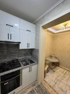 a kitchen with white cabinets and a sink and a table at Comfortable apartment in Tashkent in Yunusobod +21 photos