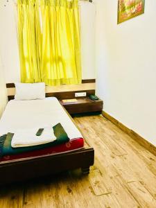 a bedroom with a bed with a yellow curtain at HOTEL SUNSHINE in Nagpur