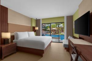 Courtyard by Marriott Phuket, Patong Beach Resort في شاطيء باتونغ: غرفة نوم بسرير وتلفزيون ومسبح