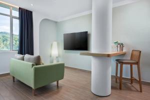 a living room with a green chair and a tv at The Bayou Hotel Langkawi in Pantai Cenang