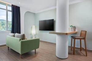 珍南海灘的住宿－The Bayou Hotel Langkawi，客厅配有绿色椅子和电视