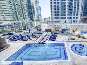 einen Pool mit blauen Liegestühlen und Gebäuden in der Unterkunft Stunning Marina View! Solo Room in Shared Apartment at Luxurious Princess Tower in Dubai