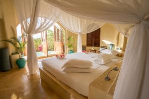 a bedroom with a white bed with a canopy at Kilindi Zanzibar in Kendwa
