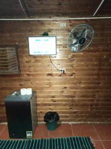 a room with a wooden wall with a television and a fan at Omar Oasis in Siwa
