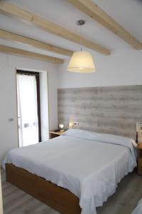 a white bedroom with a large bed and a window at Albergo Speranza in Asiago