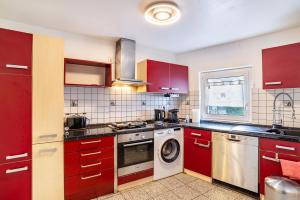 a kitchen with red cabinets and a washing machine at Haus am Bach in Haueneberstein