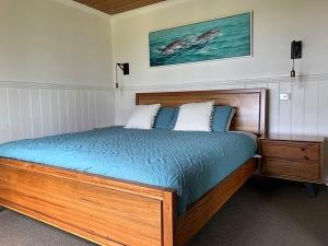 a bedroom with a wooden bed with blue sheets at Apollo Bay Cottages- Marriners in Marengo