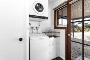 a kitchen with a sink and a washing machine at Apollo Bay Cottages- Marriners in Marengo