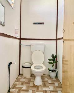 a small bathroom with a toilet and a plant at BIHING ANGAN water chalet in Semporna