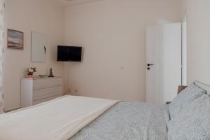 a white bedroom with a bed and a tv at La Casa di Betty in Lido di Ostia