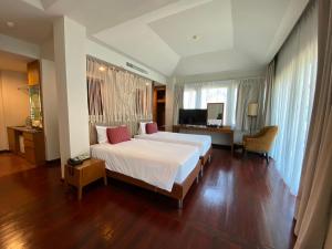 a bedroom with a large white bed and a desk at Patravana Resort in Phayayen