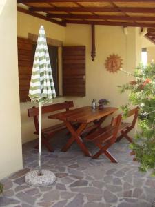 een patio met een houten tafel en een parasol bij Casa Le Basse - Vetulonia in Gavorrano