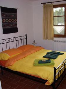 een bed met gele lakens en groene handdoeken erop bij Casa Le Basse - Vetulonia in Gavorrano