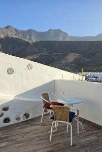 einen Tisch und Stühle auf einem Balkon mit Bergblick im Hintergrund in der Unterkunft El Nido Agaete in Agaete