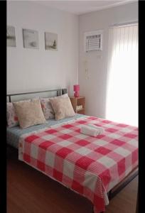 a bedroom with a bed with a red and white checkered blanket at Pine Suites Tagaytay @ RoseAna Staycation in Tagaytay