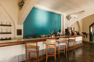 a bar with wooden chairs and a blue wall at Kilindi Zanzibar in Kendwa