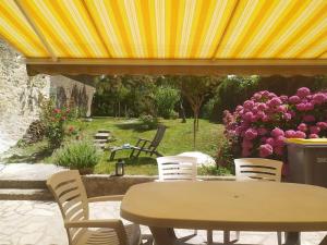 Logement avec accès terrasse في Mazières-en-Gâtine: طاولة وكراسي يجلسون تحت مظلة صفراء