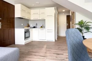 a kitchen with white cabinets and a table and chairs at Garden House - OSTOYA in Jasionka