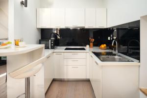 a white kitchen with white cabinets and a sink at Perla Luxury Rooms in Split