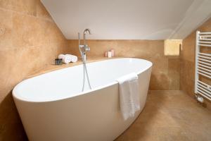 a white bath tub in a bathroom with tiles at Perla Luxury Rooms in Split