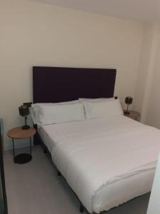 1 dormitorio con 1 cama blanca y 2 mesas en BYS SANTA FE APARTAMENTOS TURISTICOS, en Lorca