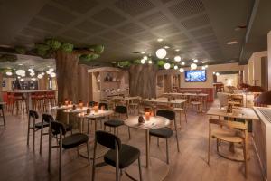 um restaurante com mesas e cadeiras numa sala com árvores em Lykke Hotel Chamonix - ex Mercure em Chamonix-Mont-Blanc
