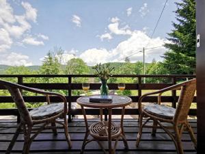 a table with two chairs and a vase of flowers on a porch at Holiday home Sovica in Vrbovsko