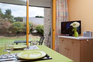 comedor con mesa, TV y ventana en Azureva Tregunc, en Trégunc