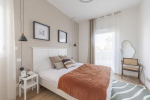 a white bedroom with a bed and a window at OVELIA Andrézieux-Bouthéon - Les Demeures du Forez in Andrézieux-Bouthéon