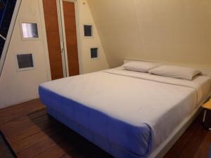 a bedroom with a white bed with a blue blanket at Locca Lodge in Mojokerto