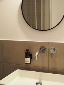 een wastafel in de badkamer met een zeepdispenser en een spiegel bij Alte Seifensiederei - Rainer Maria in Bad Tölz